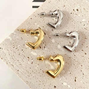 Macro view of metallic gold and silver 3D heart earrings on stone display base