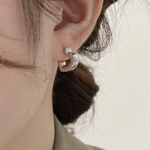 Close-up of minimalist silver hoop earrings with high-polish finish on a model's ear