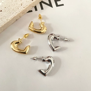 Macro view of C-shaped heart earrings in polished gold and silver metal finishes