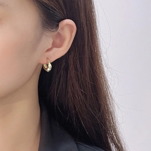 Gros plan de boucles d'oreilles dorées 18K au design goutte d'eau torsadée minimaliste