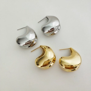 Close-up of teardrop earrings in polished gold and silver finish on a white background