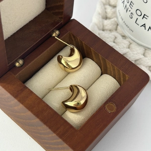 Detailed view of glossy gold crescent moon earrings displayed on a soft velvet jewelry box