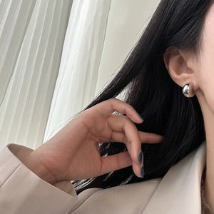 Close-up of minimalist silver spherical stud earring on model with mirror finish shine