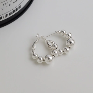 Vue macro de boucles d'oreilles créoles argentées avec perles métalliques polies miroir