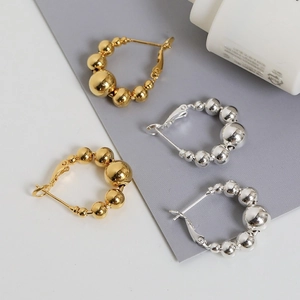 Boucles d'oreilles créoles perlées or et argent sur fond blanc au style minimaliste
