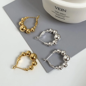 Lot de boucles d'oreilles créoles perlées en or et argent sur un support minimaliste