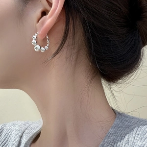 Gros plan d'une boucle d'oreille en perles argentées avec des sphères métalliques polies