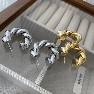 Macro shot of thick twisted rope hoop earrings in polished gold and silver finishes