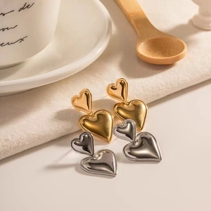 Makro-Detail von geschichteten Herzohrringen in poliertem Gold- und Silber-Metall-Finish