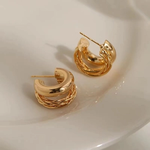 Goldene zweilagige Creolen mit gedrehter Textur auf einer Keramikschale