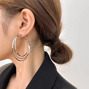 Détails de boucles d'oreilles créoles triple argent portées par un mannequin en noir