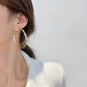Gros plan de boucles d'oreilles créoles triple couche plaquées or 18 carats sur mannequin