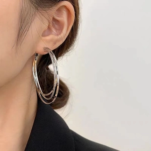Boucles d'oreilles créoles triples modernes en argent poli portées par un mannequin chic