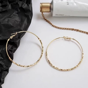 Minimalistische goldene Creolen mit kleinen Perlenakzenten auf stilvollem Hintergrund