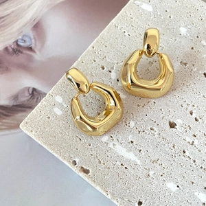 Detailed view of 18K gold plated geometric earrings on a textured stone display