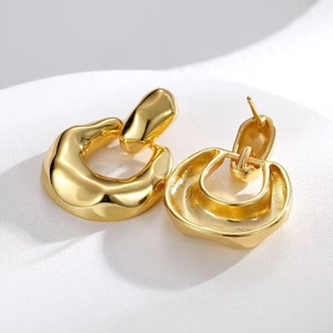 Macro view of 18K gold plated thick geometric irregular hoop earrings on display stand
