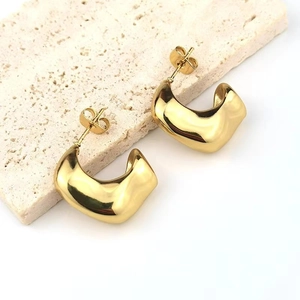 Macro detail of gold minimalist hollow crescent stud earrings with polished finish
