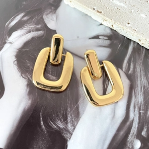 Close-up of geometric 18K gold plated earrings with a polished mirror finish on stone