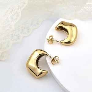 Detail of chunky gold hollow crescent earrings with high-shine lava metal texture