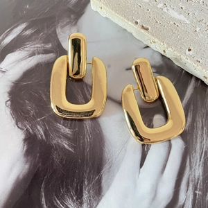 Detailed macro view of 18K gold plated geometric U-shaped earrings on textured stone