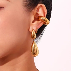 Polished gold double teardrop earrings and thick ear cuff set shown on a model