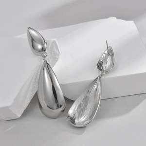 Detail of silver teardrop earrings with a mirror-polished finish on minimalist stone