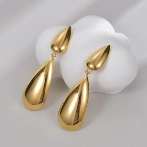 Polished gold-plated double teardrop earrings on a white decorative display stand