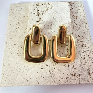 Exaggerated geometric 18K gold plated thick chunky earrings on a beige travertine stone