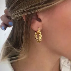 Boucles d'oreilles créoles torsadées dorées polies portées par un mannequin de mode