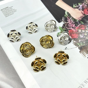 Macro shot of 18K gold and silver camellia flower earrings on a magazine background
