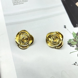 Macro shot of gold-plated rose earrings with 18K texture on a magazine background