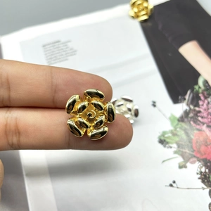 Close-up of 18K gold and silver plated camellia flower stud earrings held in hand