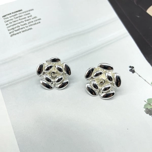 Macro detail of silver camellia flower earrings on a minimalist white magazine background