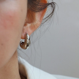 Minimalist silver teardrop earrings with a polished finish worn by a model