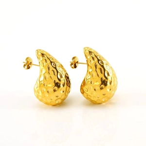 Macro shot of gold teardrop earrings featuring a unique hammered metal texture finish