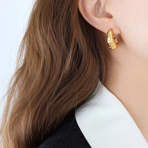Close-up of golden teardrop earrings featuring a unique textured strawberry pattern finish