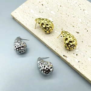 Macro detail of gold and silver teardrop earrings with unique hammered metal texture