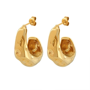 Macro detail of golden drop earrings with irregular hammered lava texture and polished finish