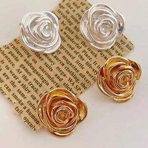 Retro 18K gold and silver camellia flower stud earrings set on vintage newspaper background