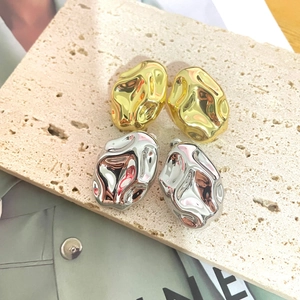 Macro detail of irregular lava texture earrings in polished gold and silver finishes
