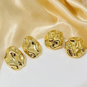 Close-up of golden irregular textured earrings with liquid metal mirror finish