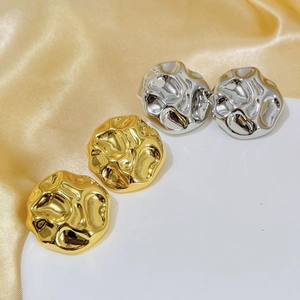 Detailed view of hammered gold and silver irregular earrings on silk fabric