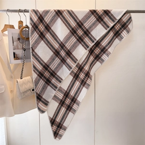 Detailed view of classic plaid scarf texture and fine knit hem in earthy brown tones