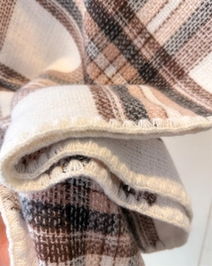 Detailed close-up showing the soft plaid knit fabric and fine stitched edges of the scarf
