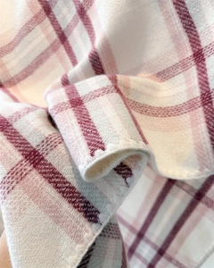 Macro detail of pink plaid cashmere-feel scarf showing soft texture and neat stitching