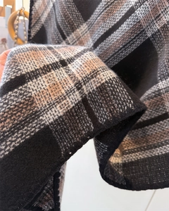 Close-up of thick plaid cashmere-like scarf showing warm orange and grey knit texture