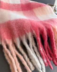 Gros plan sur l'écharpe à carreaux rose et crème avec pompons épais et texture mohair