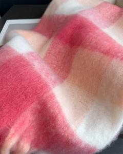Gros plan sur la texture douce en mohair de cette écharpe à carreaux rose et blanc