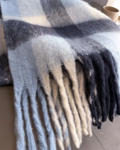 Gros plan sur une écharpe à carreaux bleus et blancs avec des détails de longues franges