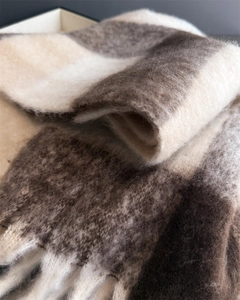 Gros plan d'une écharpe épaisse à carreaux en mohair doux, tons marron chaud et beige
